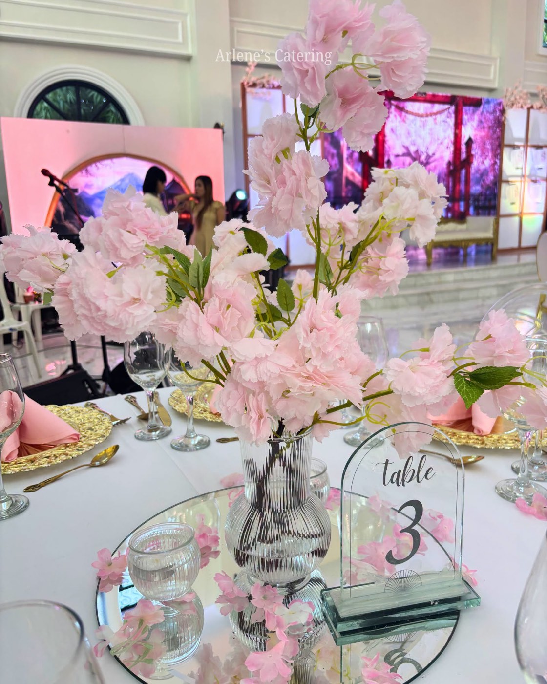A real reception table with a Table 3 marker, cherry blossom centerpiece, guests visible