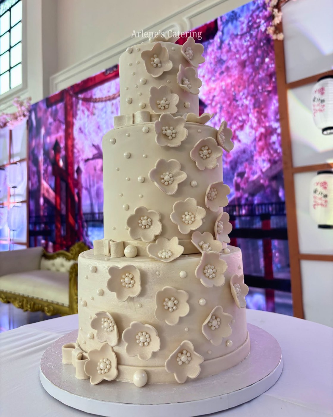 A real wedding cake at an Arlene's Catering reception, cherry blossom uplighting in the background