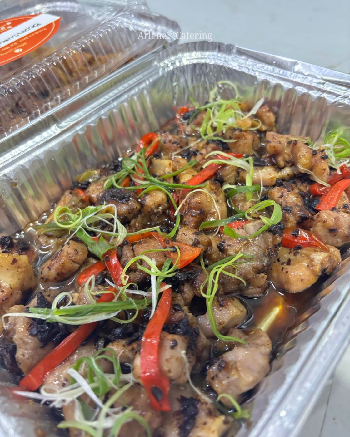 A chicken dish with chili and scallions in a catering tray