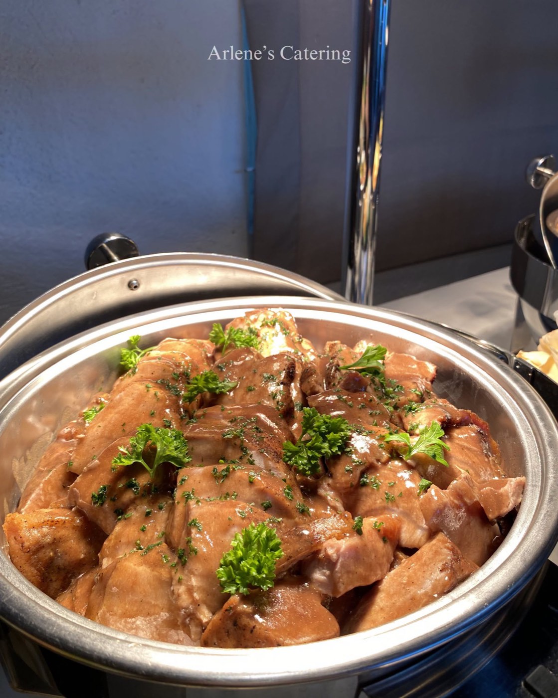 A chicken dish with lemon garnish in a catering tray