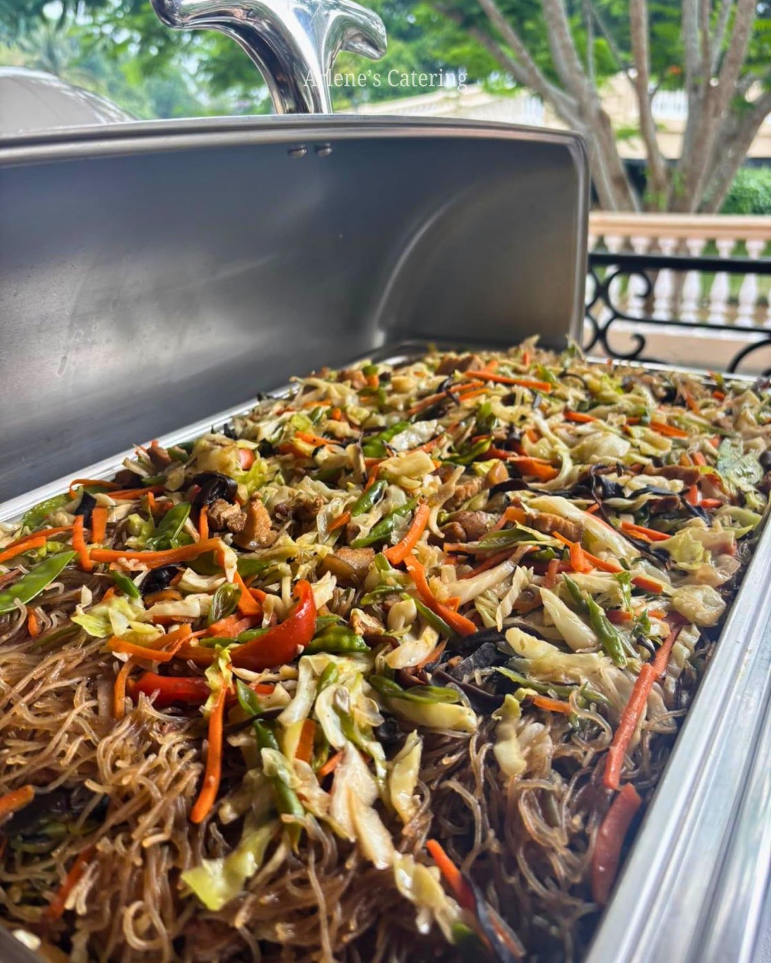 A tray of pancit noodles in a catering chafing dish