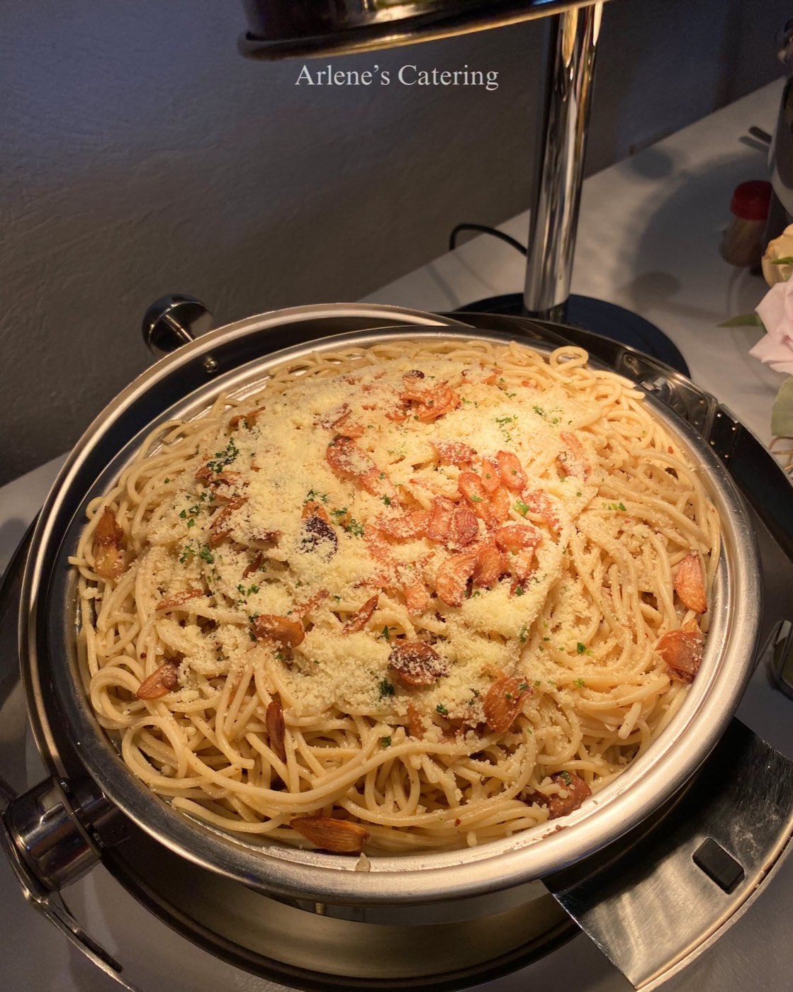 A pasta dish with herb garnish in a catering chafing tray
