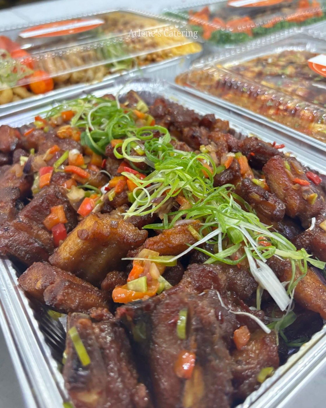 A pork dish with sausage and pasta in a catering tray