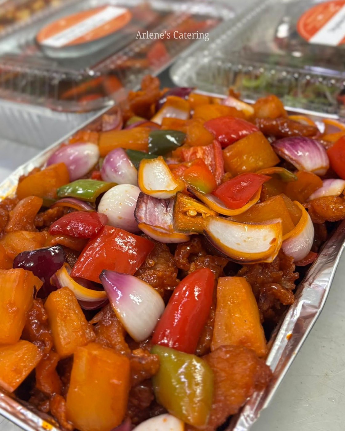 A mixed vegetable dish with bell peppers in a catering tray