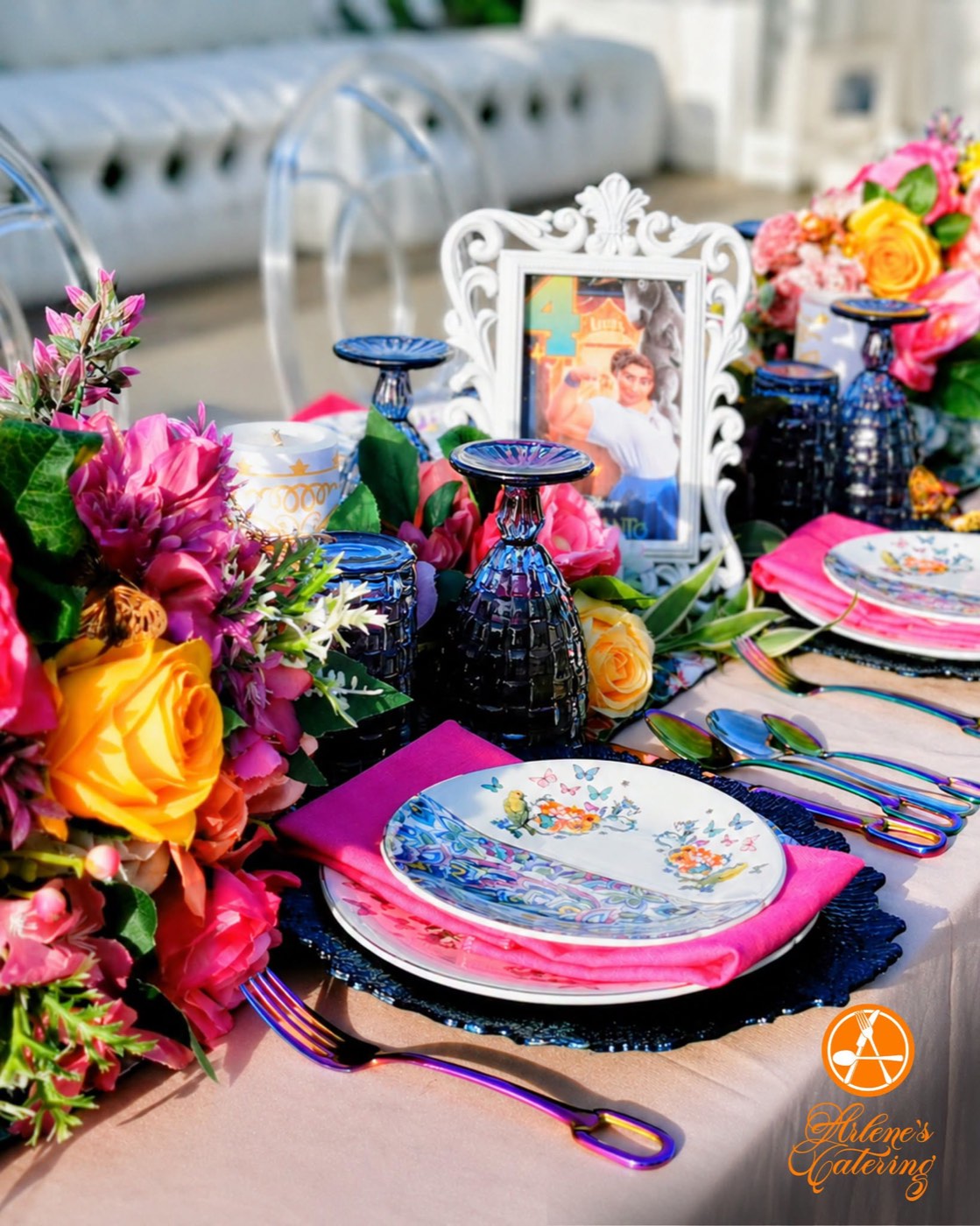 A colorful floral reception tablescape with patterned plates and gold accents