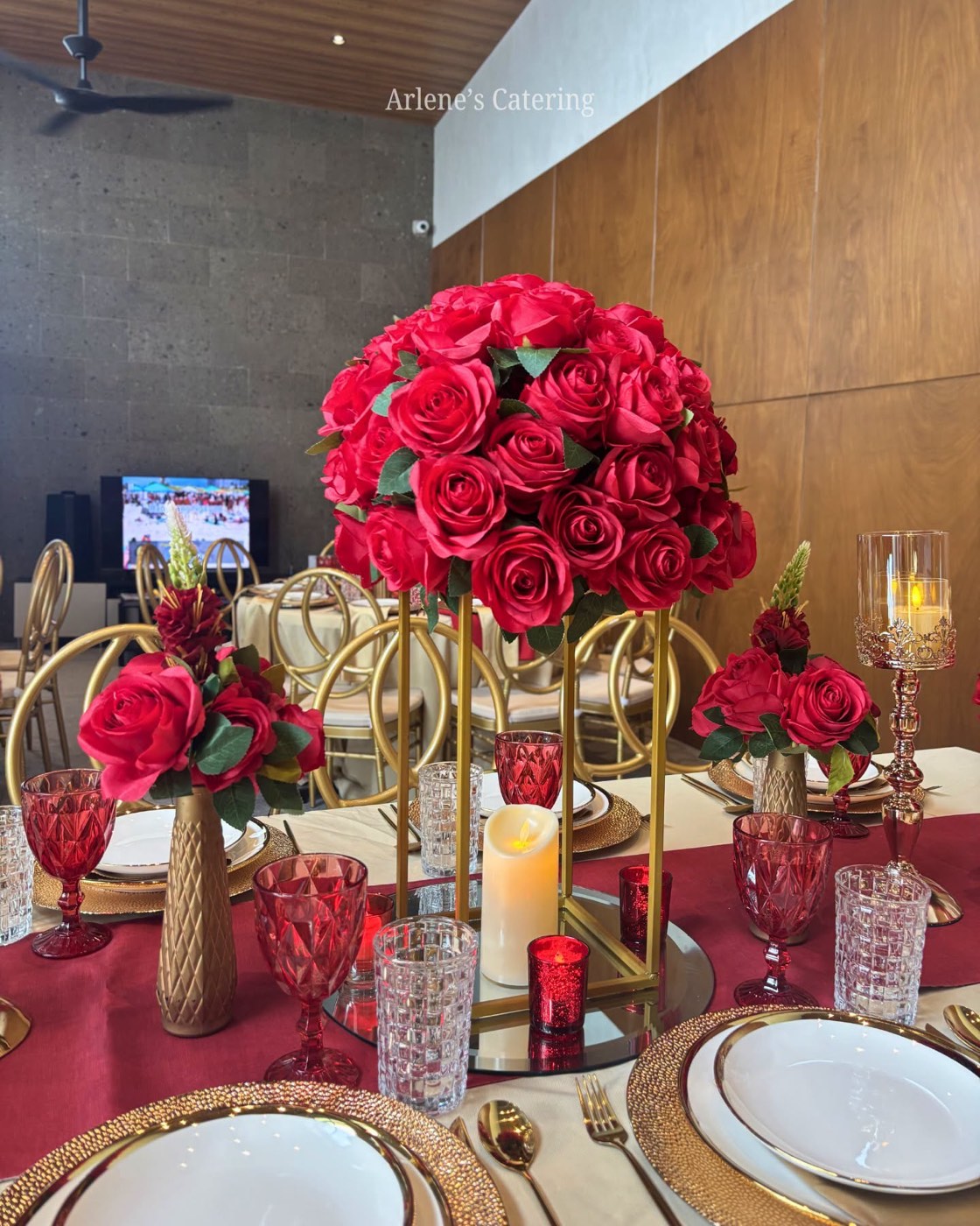A deep wine and gold reception tablescape with red rose centerpieces and candelabra